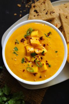 a white bowl filled with soup next to crackers