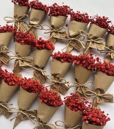 small cones with red berries tied in twine on white tablecloth and brown paper tags