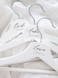 three white wooden hangers with names on them