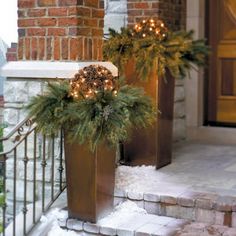 two planters with christmas decorations on the front steps