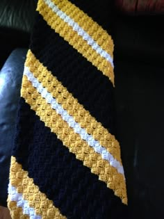 a black, yellow and white crocheted tie sitting on top of a couch