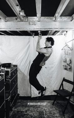 a man standing on top of a chair in front of a white wall and ceiling