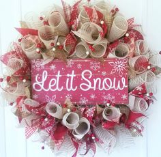 a wreath that says let it snow on the front door with red and white ribbons