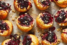 small pastries with cranberry toppings are on a baking sheet, ready to be eaten