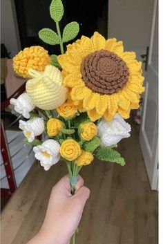 a hand holding a crocheted sunflower bouquet