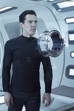 a man standing in front of a mirror holding a device with his hands on his hips