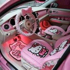 the interior of a pink car with hello kitty steering wheel covers and matching dashboard mats