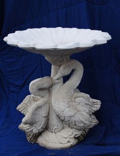 a white bird statue holding a bowl on it's back