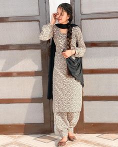 a woman standing in front of a door wearing a black scarf and dress with leopard print on it