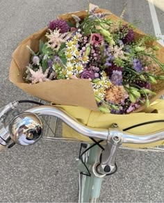 a bouquet of flowers is sitting on the handlebars of a bicycle