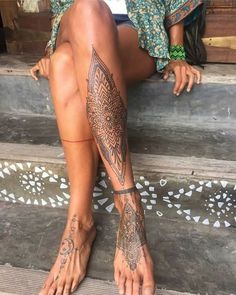 a woman's legs with tattoos on them sitting on the steps next to stairs