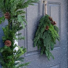 two wreaths hanging on the front door with pine cones and evergreen branches attached to them