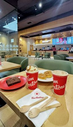 a table with two cups of coffee and some pastries on it in a restaurant