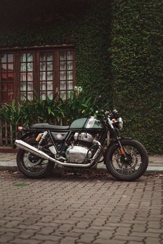 a motorcycle is parked on the side of the road next to a building with ivy covered windows