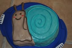 a blue plate topped with a cake covered in frosting and a snail on top