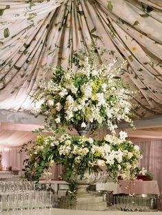 a large vase with white flowers sitting on top of a table next to wine glasses