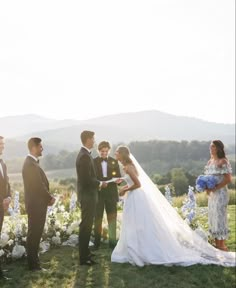 a bride and groom standing in front of their wedding party at the end of an outdoor ceremony