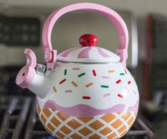 a tea pot with a pink handle and sprinkles on the inside is sitting on top of a stove