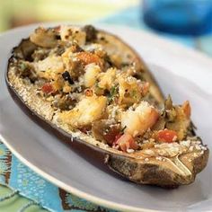 a white plate topped with an eggplant covered in stuffing