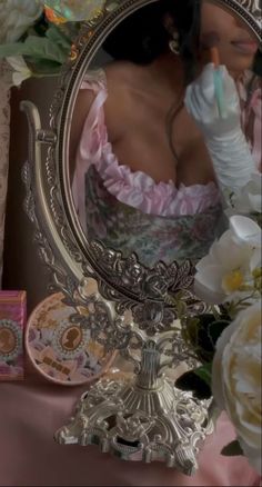 a woman in a pink dress is looking at herself in the mirror with gloves on