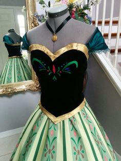 a green and gold dress on display in front of a mirror