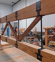 a man standing next to a large wooden beam in a room filled with wood planks