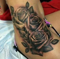 a woman's thigh with three roses tattoo on her side and the lower half of her leg