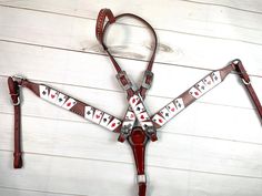 a red leather harness with playing cards on the front and sides, attached to a white wooden wall