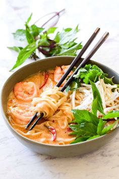 a bowl filled with noodles and shrimp next to chopsticks on top of a table