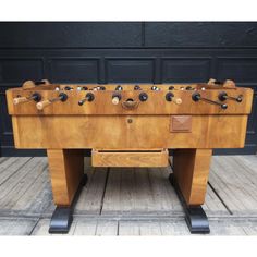 an old fashioned foosball table sitting on top of a wooden floor next to a black door