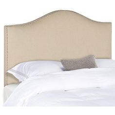 an upholstered headboard on a bed with white linens and gray pillows