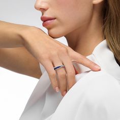 a woman wearing a white shirt with a blue ring on her finger