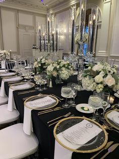 the table is set with white flowers and black linens for an elegant wedding reception