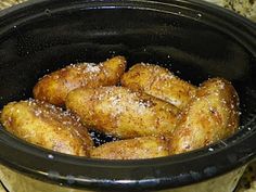 some fried food in a black crock pot on a counter top with salt and pepper sprinkles