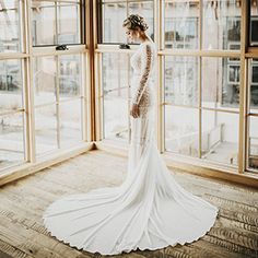 a woman in a wedding dress looking out the window