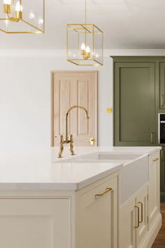 a kitchen with green cabinets and white counter tops, gold accents on the handles and brass fixtures