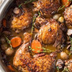 some meat and vegetables in a pot on the stove with broth, carrots and mushrooms