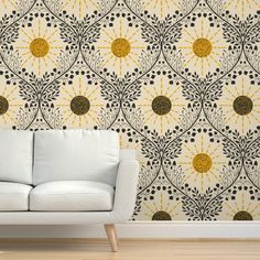 a white couch sitting in front of a wall with a yellow and black pattern on it