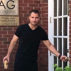 a man holding a bottle in front of a brick building with a sign on it