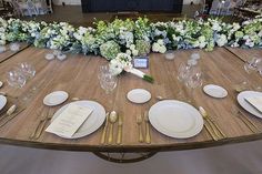 the table is set with white and green flowers on it, along with silverware