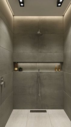 an empty bathroom with no shower curtain and lights on the ceiling, along with white tile flooring