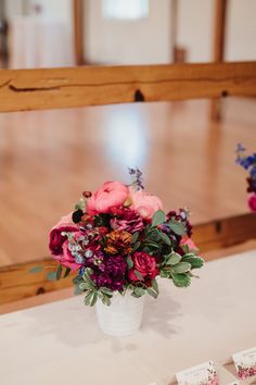 a vase filled with lots of flowers on top of a table next to place cards