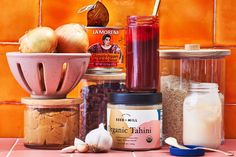 an assortment of food items sitting on a counter top next to jars and spoons