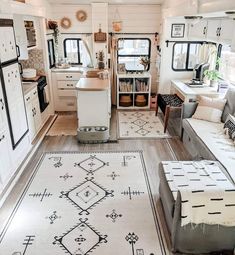 the interior of a mobile home with white furniture and rugs on the wood floor