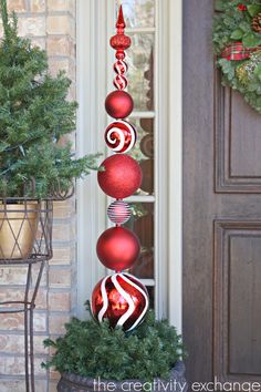 a tall red and white christmas ornament on top of a planter in front of a door