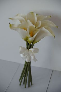 a bouquet of white flowers with a bow on the end is sitting on a table