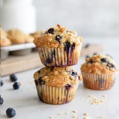 three blueberry muffins stacked on top of each other with oats scattered around them