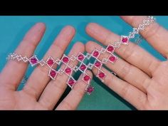 a hand holding a silver chain with red stones on it