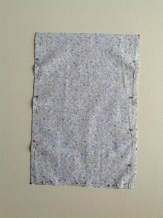 a piece of cloth with small blue flowers on it sitting on a table next to a wall