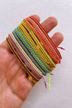 a hand holding a stack of multicolored bracelets